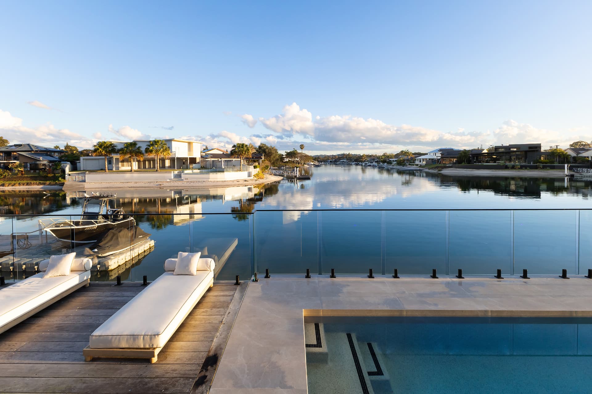 The pool and day beds with a boat on the pontoon and the canal running to open water