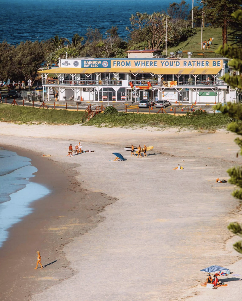 Rainbow Bay surf club and the sand seen from the headland above