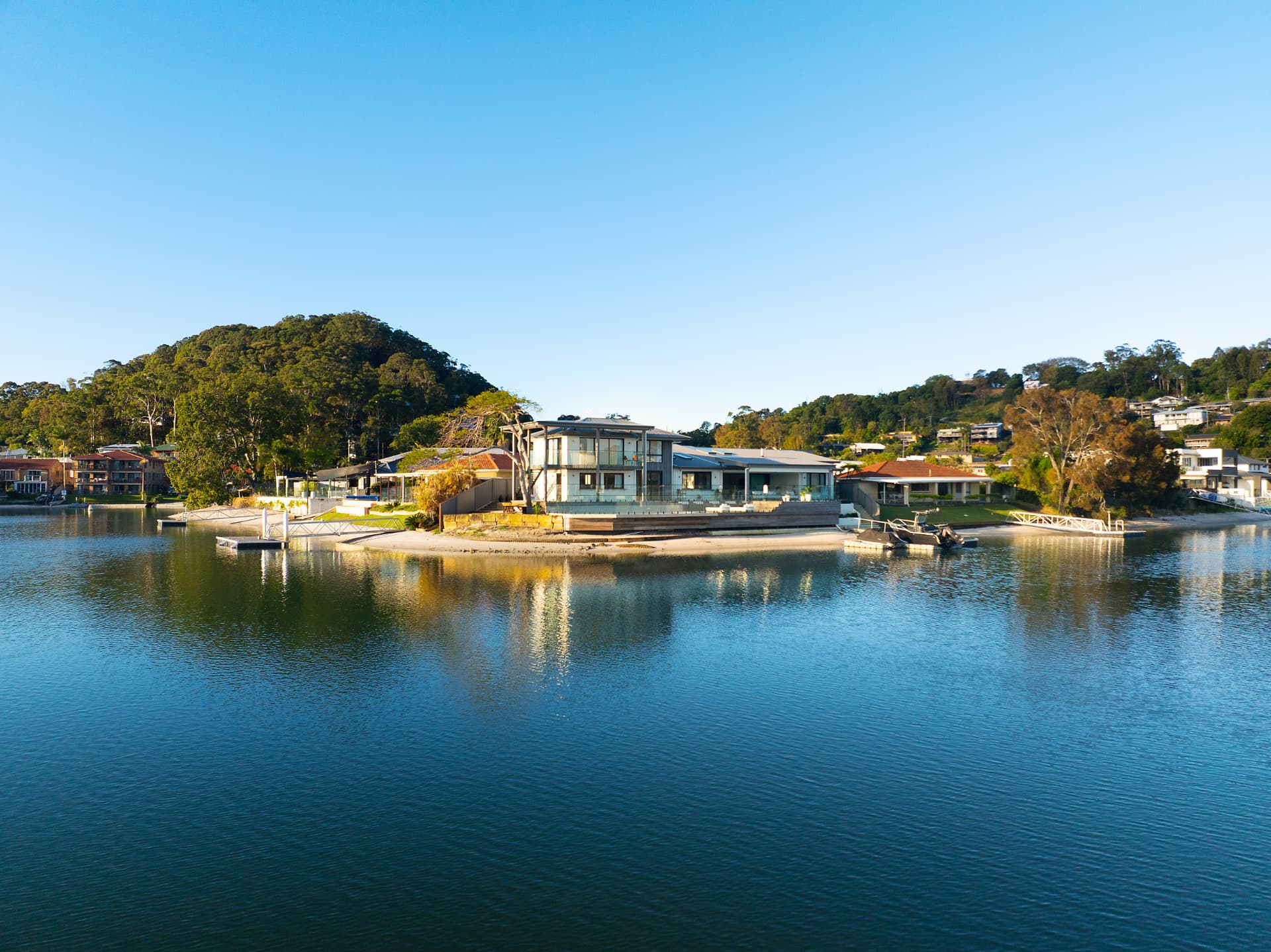 The house from across the water on a clear morning, deck and pontoon on still canal