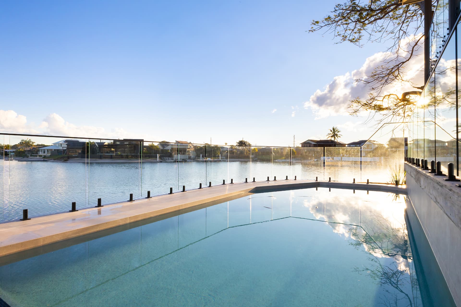 The pool at sunset, glass fence, still canal water beyond