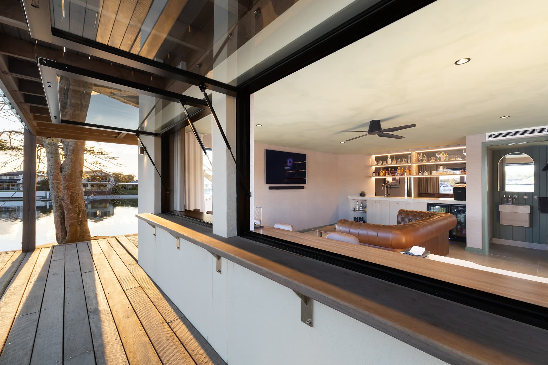The bar room seen from the deck, backlit shelving, leather banquette and servery window