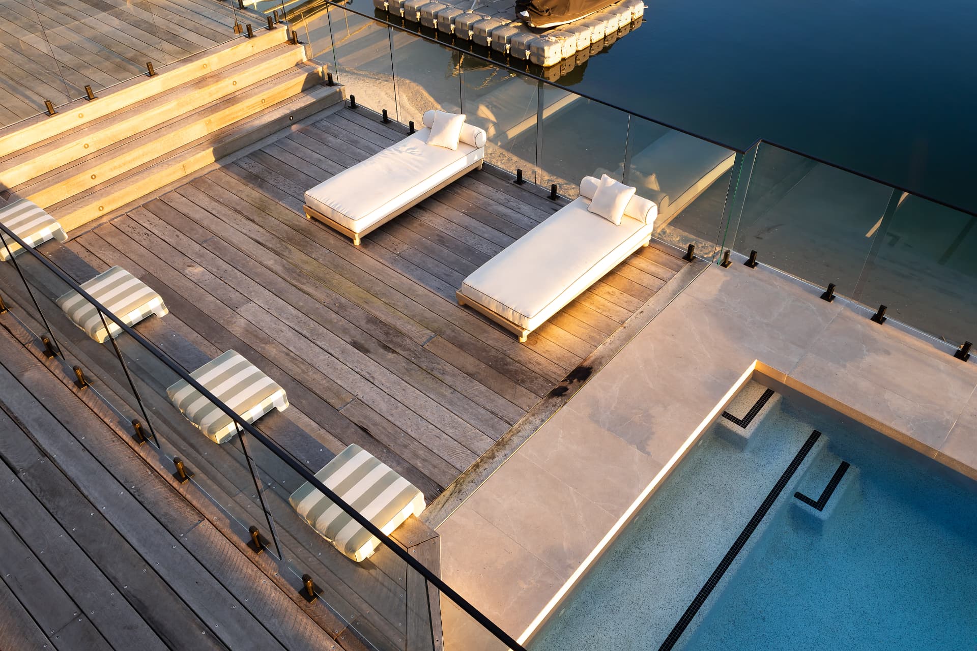 The deck from above, day beds and striped bench cushions beside the pool